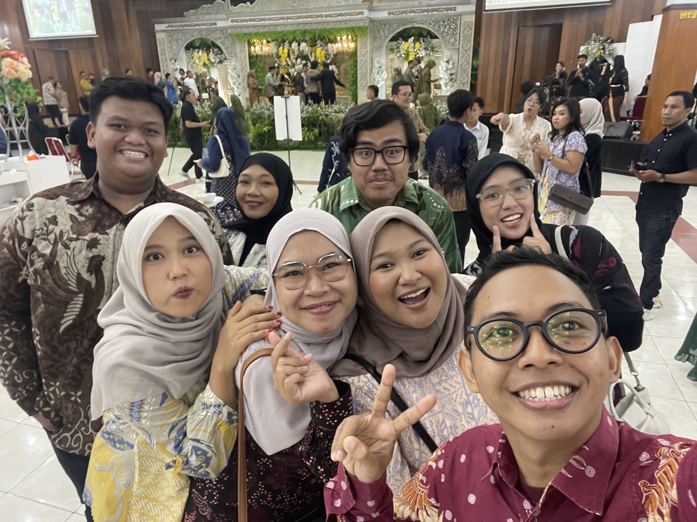 Rombongan tamu berswafoto di resepsi, slideshow tampil di layar kanan atas